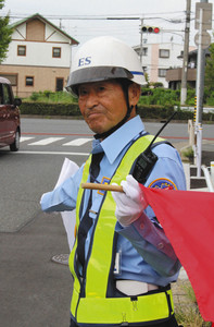 白と赤の旗を振って交通誘導をする中島芳之さん＝名古屋市で