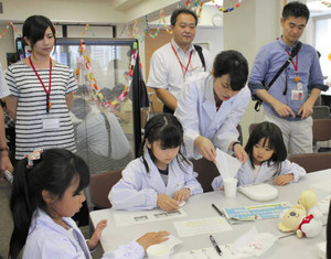 親に見守られながら調剤体験をする子どもたち＝東京都千代田区の協和発酵キリンで