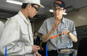 後輩たちに仕上げ作業を教える藪田さん（右）＝名古屋市北区の愛知工業高校で