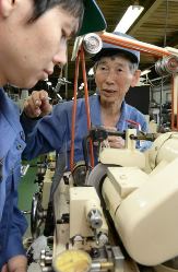 研磨の仕方を若手に教えるベテラン従業員の上島幸紀さん（右）＝名古屋市港区の渡辺精密工業で