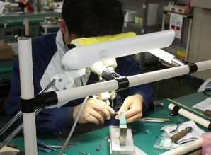 顕微鏡を使って、脳神経外科手術用剪刀の刃先を磨く従業員＝鯖江市川去町のシャルマンで