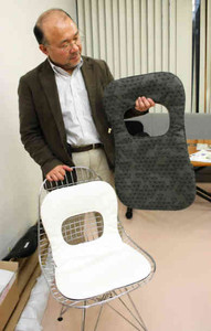 片岡哲さんがデザインした新作のクッションを手にする酒井敏光さん＝いずれも坂井市丸岡町北横地で