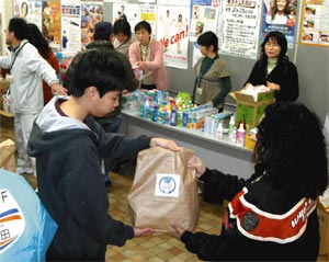 来庁者に食料品の袋を手渡すスタッフ（左）＝磐田市役所本庁舎で