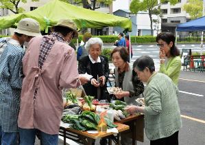 エプロン姿で野菜などを販売する訓練校の人たち（左側）＝熱田区旗屋町の想念寺で