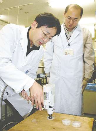 遺伝子銃でＧＦＰ遺伝子をネギに打ち込む小泉周准教授（左）と森藤暁さん＝岡崎市の自然科学研究機構生理学研究所で