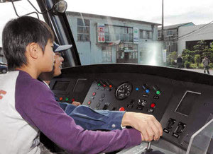 アイトラムを体験運転する子ども（手前）＝高岡市荻布の万葉線本社前で