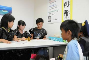 裁判所に見立てた部屋で、ルール違反の罰金刑を審議する裁判官役や警察官役の子ら＝岡崎市西蔵前町で