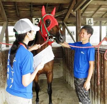 馬体のチェックを体験する藤本優さん（右）＝笠松町の笠松競馬場で