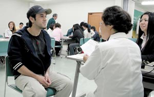 病院を訪れたという想定で、元小児科医師の山本和子さん（中）と日本語でやりとりする受講者（左）＝浜松市中区の伸栄総合サービスで