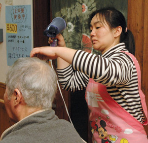 お年寄りのぬれた髪を乾かす日系人の研修生＝鈴鹿市秋永町で