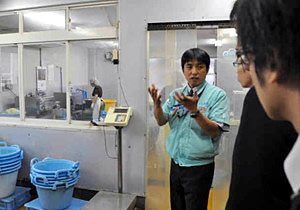 作業場で、説明を受けながら作業工程を見学＝金沢市駅西本町で