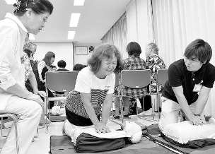 参加者に胸骨圧迫を指導する内田さん(右)＝瑞穂区の御剣コミュニティセンターで