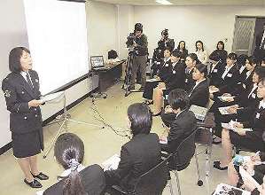 女性警察官（左）の説明を聞く参加者たち＝名古屋市中区の県警本部で
