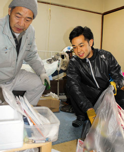 「御用利きと出前授業」のボランティア会員と一緒に部屋の片付けをする加藤幹泰さん（右）＝名古屋市で