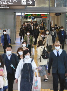 政府の緊急事態宣言が全国に拡大された翌日、マスク姿で出勤する人たち＝１７日、名古屋市中村区で