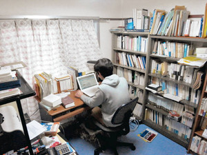 「研究室」である自宅の机でパソコンに向かう非常勤講師の男性。仕事関係の出費は自腹が多い＝関西地方で