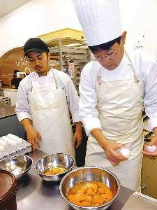 小笠原さん（左）の指導を受け、ケーキ用の卵を割る作業に取り組む＝東海市加木屋町で