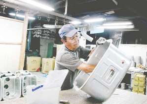 金属部品を磨く吉留重利さん＝愛知県春日井市で