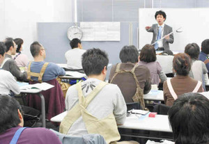 介護現場と同じエプロン姿で介護福祉コースの講義を聞く受講者ら＝名古屋市西区で