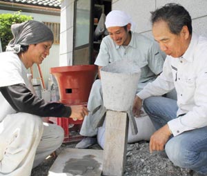 花器を塗って壁塗りの練習をする●林さん（左）と、見守る桑原さん（中）と水野社長＝浜松市南区新貝町で