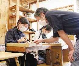 職人から助言を受けながら木材を彫る大学生たち＝中区橘２の京屋伊助商店で