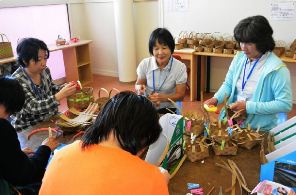 ペーパーバンドを素材にしたかごを作る利用者と職員＝美濃加茂市森山町で
