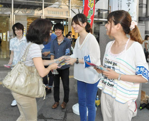 「看板娘」の情報提供を呼び掛けてチラシを配る学生ら＝豊橋駅前で