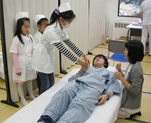 理学療法士体験で患者の腕を曲げ伸ばしする子ども＝金沢市法島町で