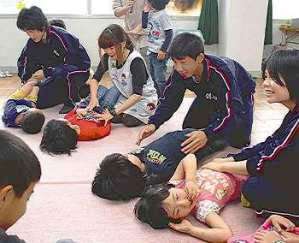 保育士に習って、子どもと触れ合う中学生たち＝松阪市京町１区で