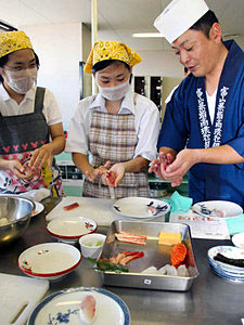 職人の手ほどきを受けてすしを作る生徒＝富山市の県民会館で