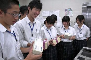 お札の束を持って、重みを実感する生徒たち＝養老町押越で