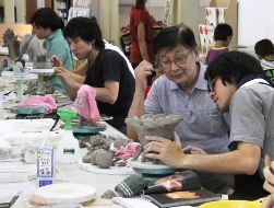 瀬戸窯業高専攻科の生徒たちに、瀬戸ノベルティの作り方を教える武田さん（右から２人目）ら＝瀬戸市泉町のノベルティ・こども創造館で