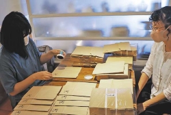 支援員に見守られながら作業する女性利用者(左)=昭和区の「おうち菓子 マダムアン」で