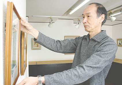 企画展の展示作業をする久保田達郎さん＝豊橋市駅前大通で