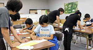 学芸員の指導を受けながら、かぶとを作る児童たち＝高岡市立博物館で