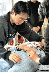 講師から指導を受け、被介護者の衣類を交換する中田成信さん（左）＝福井市の県社会福祉センターで
