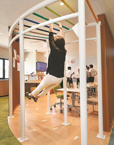 昼休みに、うんていで体を伸ばすフジクラの女性社員＝東京都江東区で