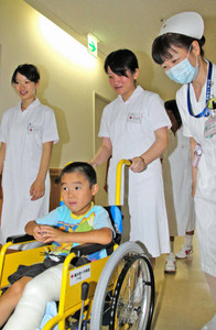 看護師（右）からアドバイスを受け、患者の車いすを押す生徒＝福井市月見２丁目の福井赤十字病院で