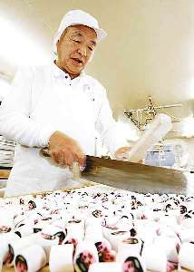 棒で包丁をたたき、金太郎飴を刻む渡辺鉄男さん＝東京都台東区で