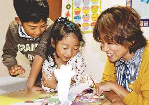 飛び出す絵本などを使い、楽しんでもらいながら英語の楽しさを伝える南出さん（右）＝名張市で