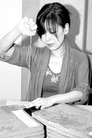古書の修復作業で糸のとじ直しをする林知左子さん＝西尾市の岩瀬文庫で