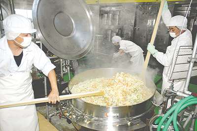 「スパテラ」を使って、いためそば作りに取り組む人たち＝豊橋市西部学校給食共同調理場で