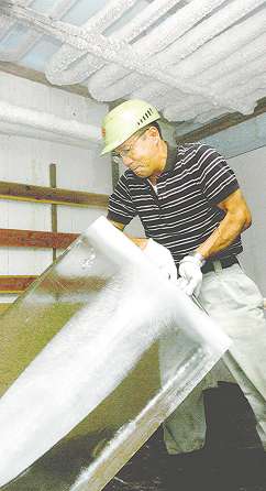 ６０時間かけて作った氷を持ち上げ、貯氷庫に並べていく松井博司さん＝豊橋市湊町の大正冷蔵で