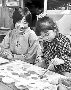 「ぬらし絵」に取り組む子どもを笑顔で見守る谷口薫子さん（左）＝新城市吉川で