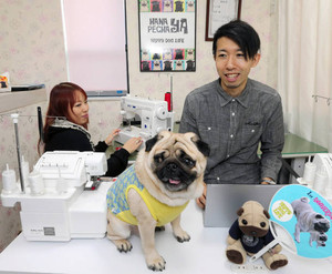 副業で犬用グッズのネットショップを開く山崎俊彦さん（右）と妻の亜紀子さん。愛犬の次郎がモデルを務める＝東京都品川区で