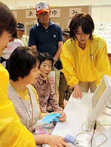機器を使って血管年齢を調べる人たち＝富山市新富町で