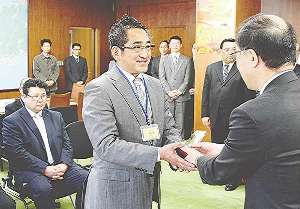 山本雅史局長からトロフィーを受け取る物語コーポレーションの加治幸夫社長（中）＝名古屋市中区の中部経済産業局で