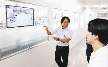 学生に工場を案内するアドバンス電気工業の担当者（左）＝春日井市廻間町で