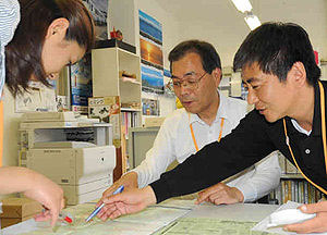 氷見の観光マップを見ながら研修する大江さん（中）＝氷見市観光案内所で