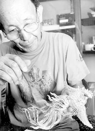 熟練の筆さばきで余分な金箔を払う都築一三さん。無風の工房に、きらきらと破片が舞う＝幸田町の都築仏壇店で